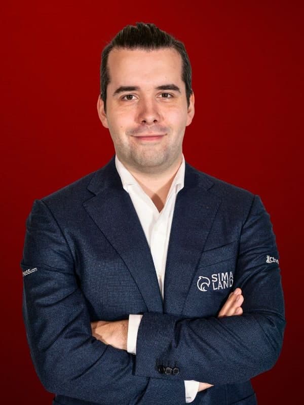 Ian Nepomniachtchi in a navy blazer, arms folded, against a red studio backdrop