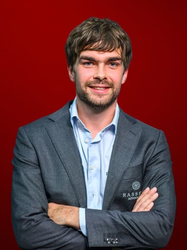 Jorden van Foreest in a grey blazer, arms folded, against a red studio backdrop